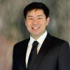 Michael Lau in a dark suit against a studio backdrop.