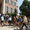 A group of first-year students walking into the Koelbel Building on a sunny day.