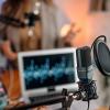 A host and guest prepare for a podcast interview in a studio.