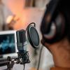 A creator speaks into a microphone in a podcasting studio.