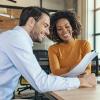 A man and young woman work together on a project in a modern office space.