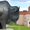 A beautiful spring day on the CU Boulder campus. Focus on a buffalo statue in the foreground; the Koelbel Building visible in the background.