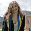 Olivia posing in graduation regalia outside the Koelbel Building.