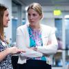 Three female professionals in business attire chat in a corridor in the Koelbel Building.