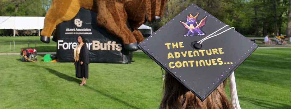 student with a graduation cap that says 'the adventure continues"
