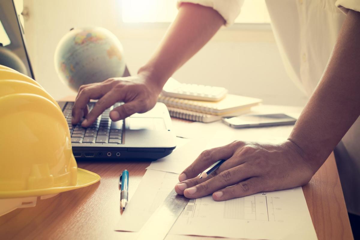 a laptop on a desk with a globe and hardhat