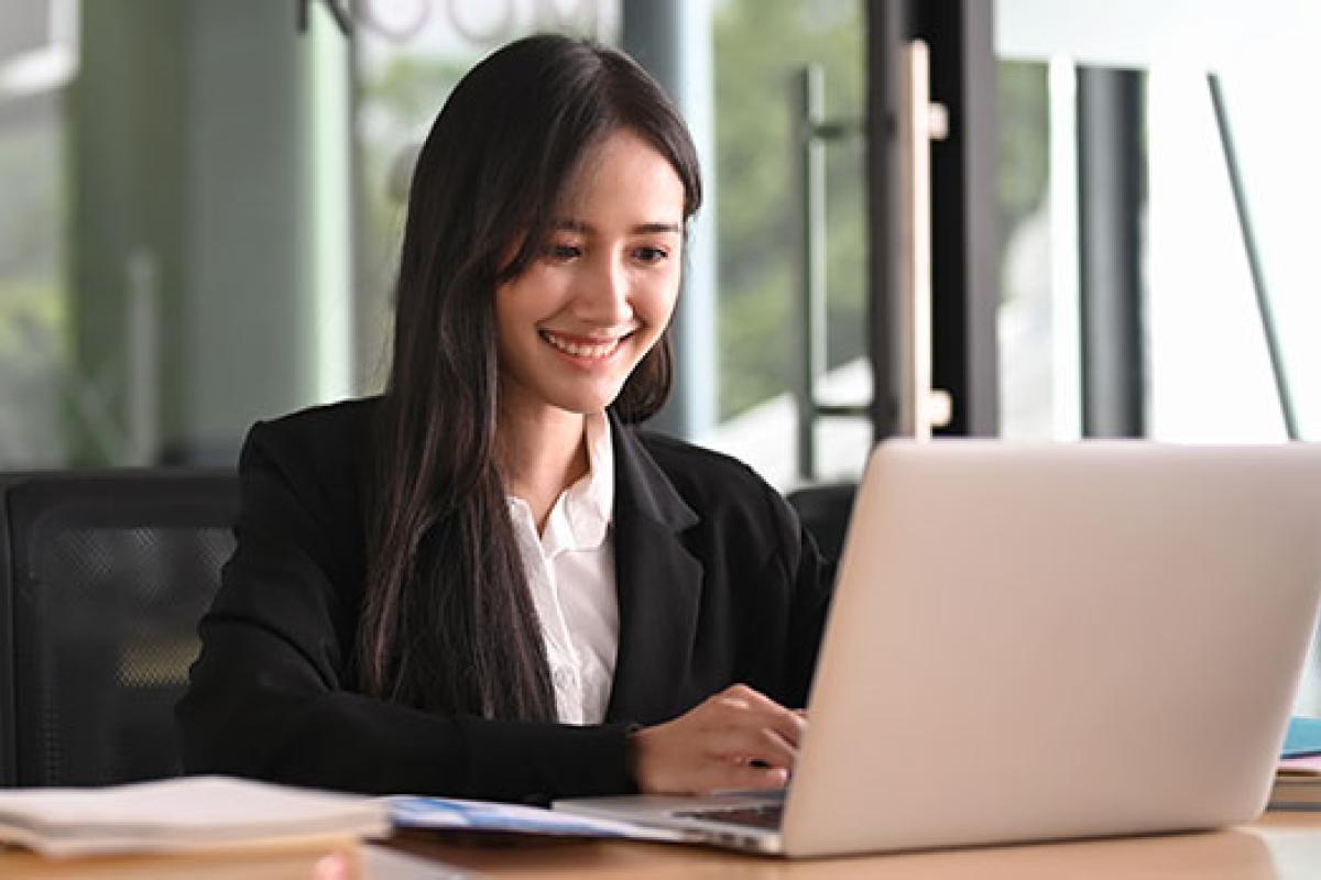 person typing on a computer while sitting at a wooden desk