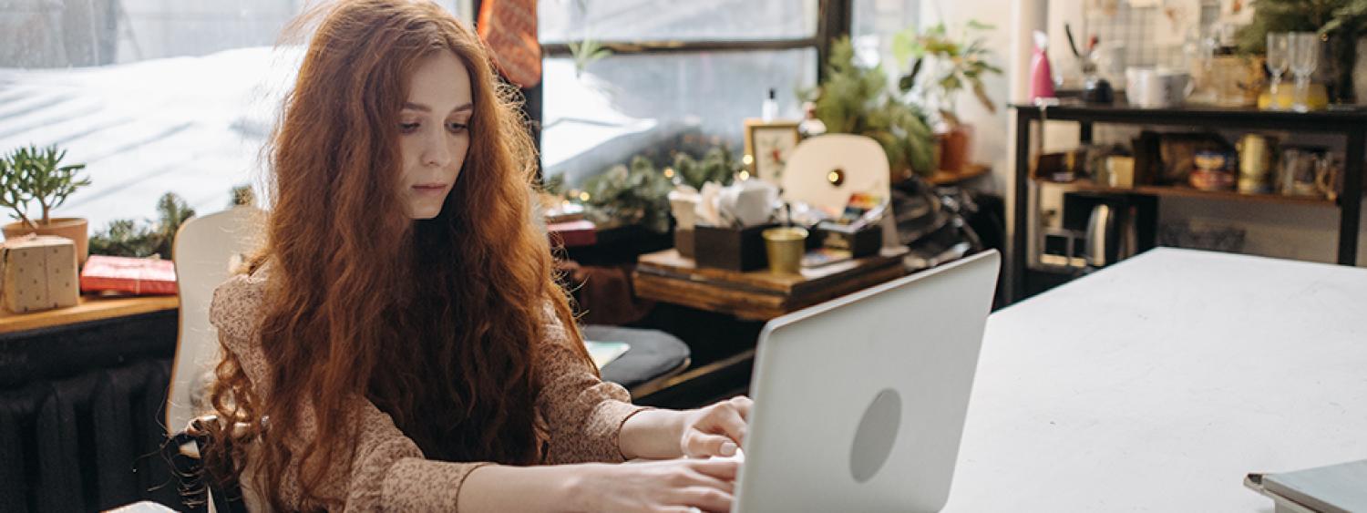 a woman with long red hair working on a laptop