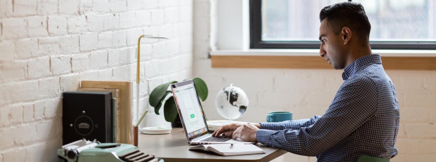 Male student sitting at a desk working on a computer