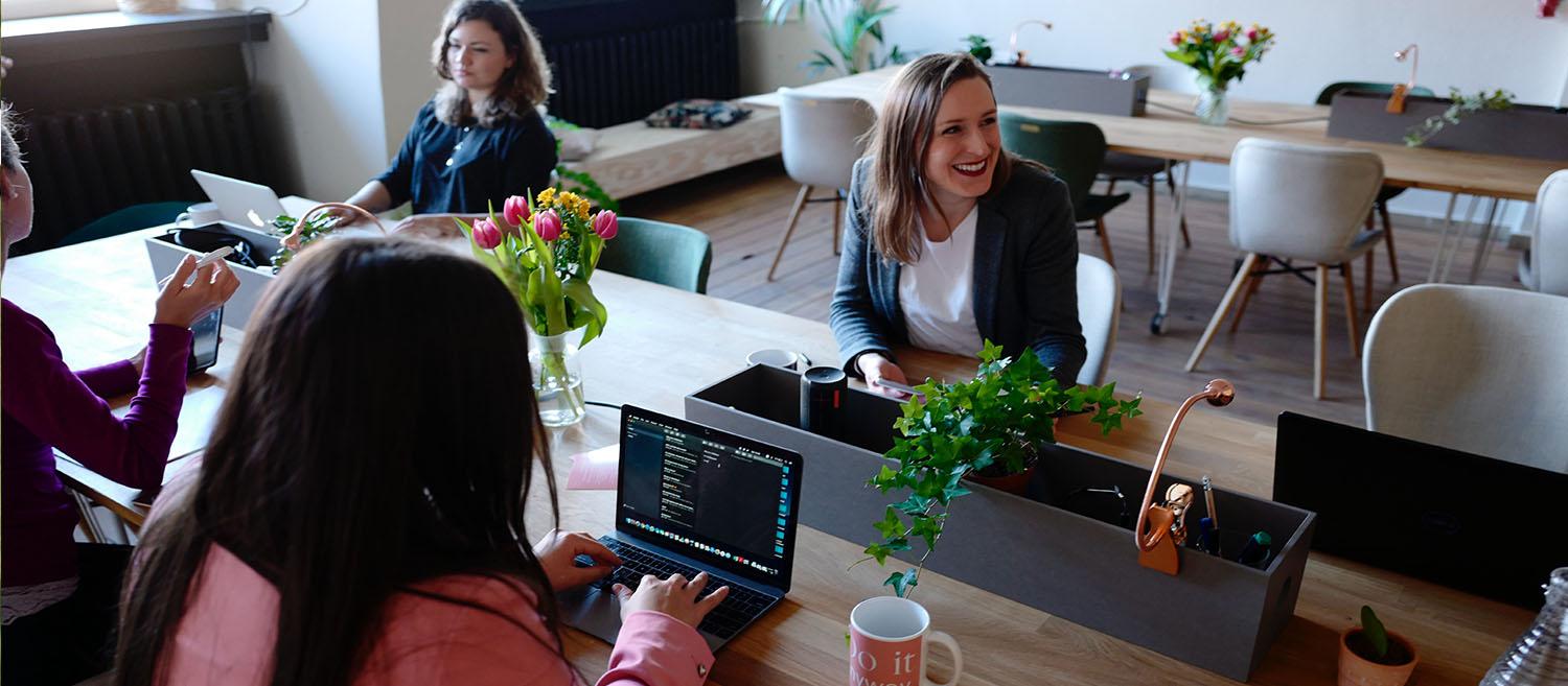 group of people sitting at a desk with laptops