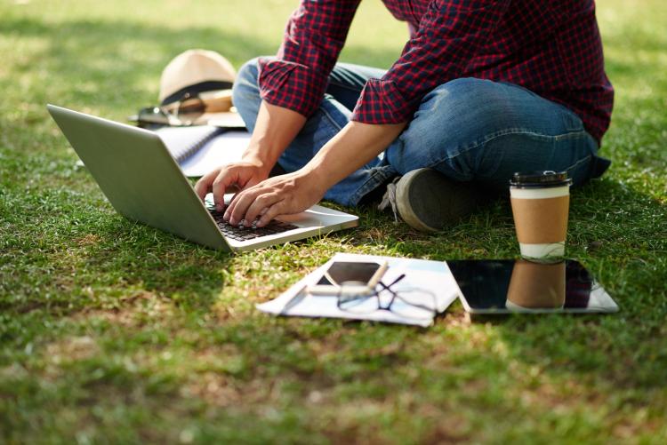 Person sitting on the grass with a laptop
