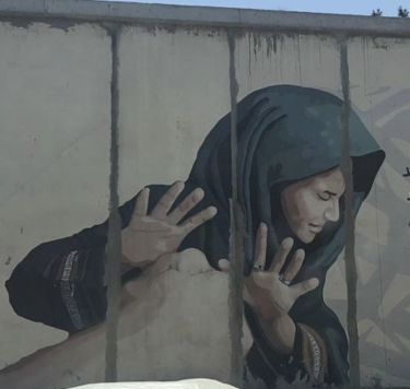 mural depicting a woman in a hijab running with hands protecting face