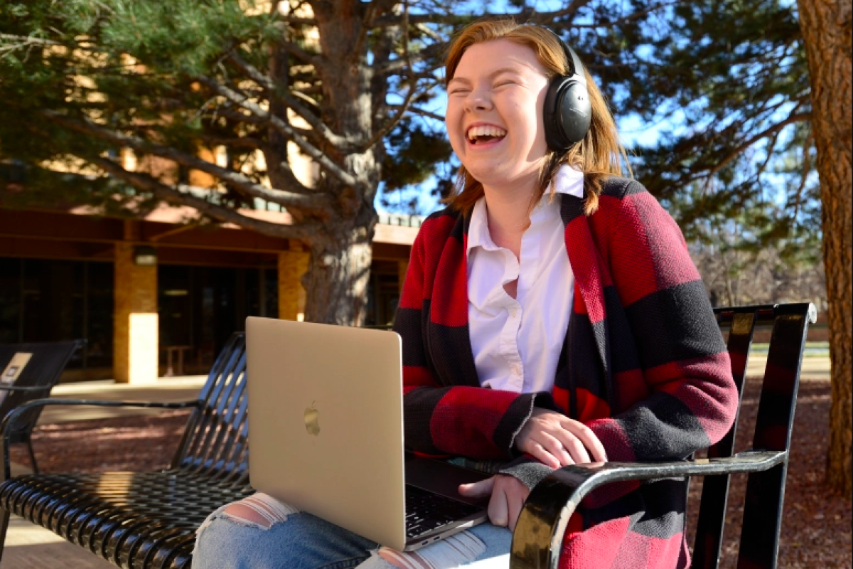 Young adult listening with headphones at laptop