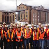 Group of people wearing construction vests and helmets.