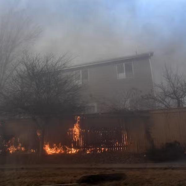 A fence on fire near a home during the Marshall Fire