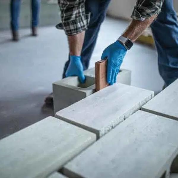 Person with gloves on handling blocks of concrete