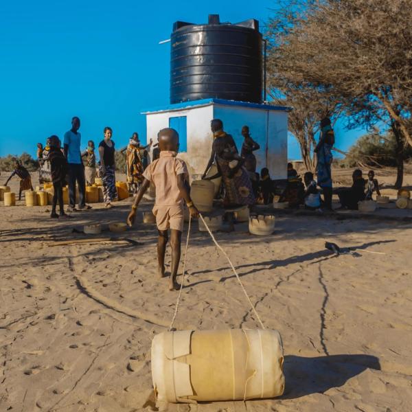 People lining up with plastic jugs to collect water.