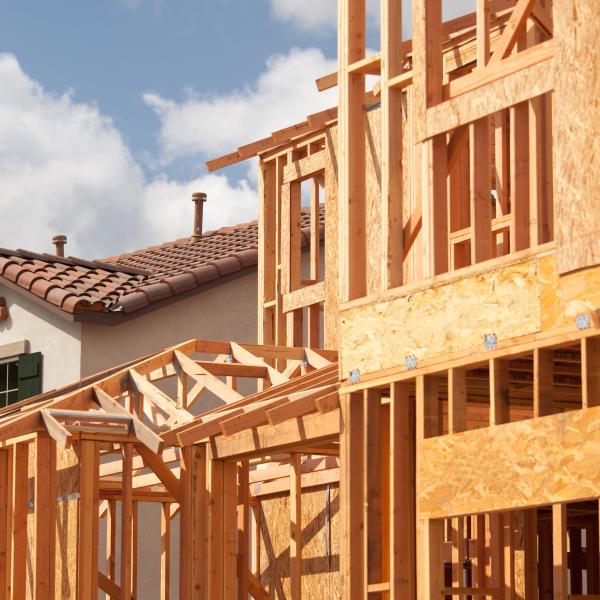 An unfinished, framed home next to a completed home