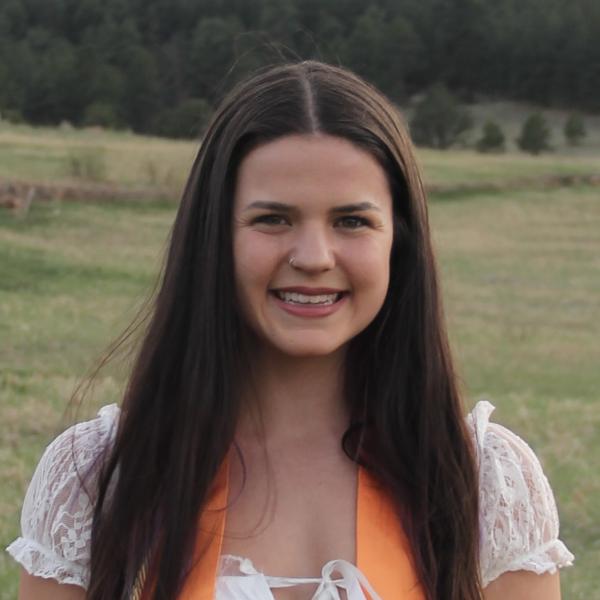 Jenna Stein with a field and base of the mountains in the background.