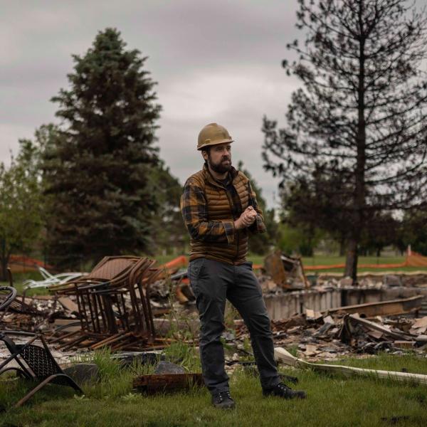 Brad Wham in a hard hat in a neighborhood burnt by the Marshall Fire