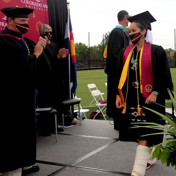A student crosses the stage to receive her diploma during the graduation ceremony at CMU