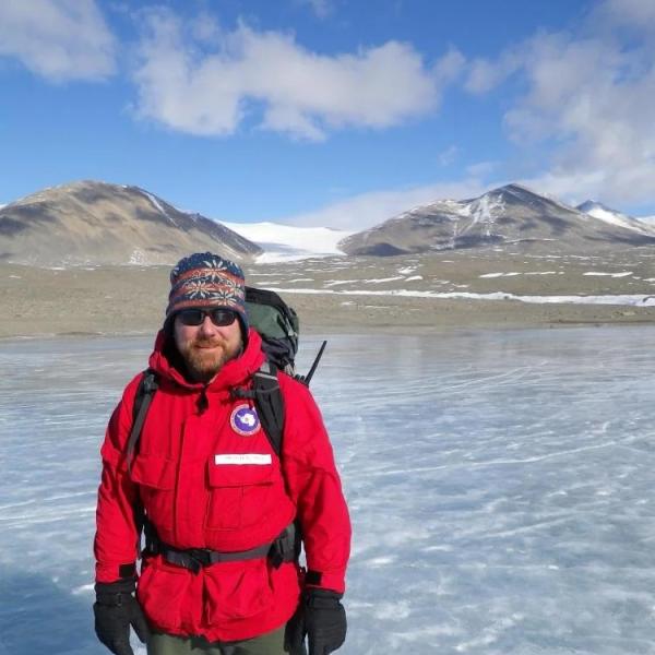 Michael Gooseff in a winter hat and parka standing on an ice sheet in Antartica
