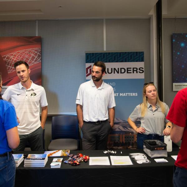 Conference participants visiting Saunders table
