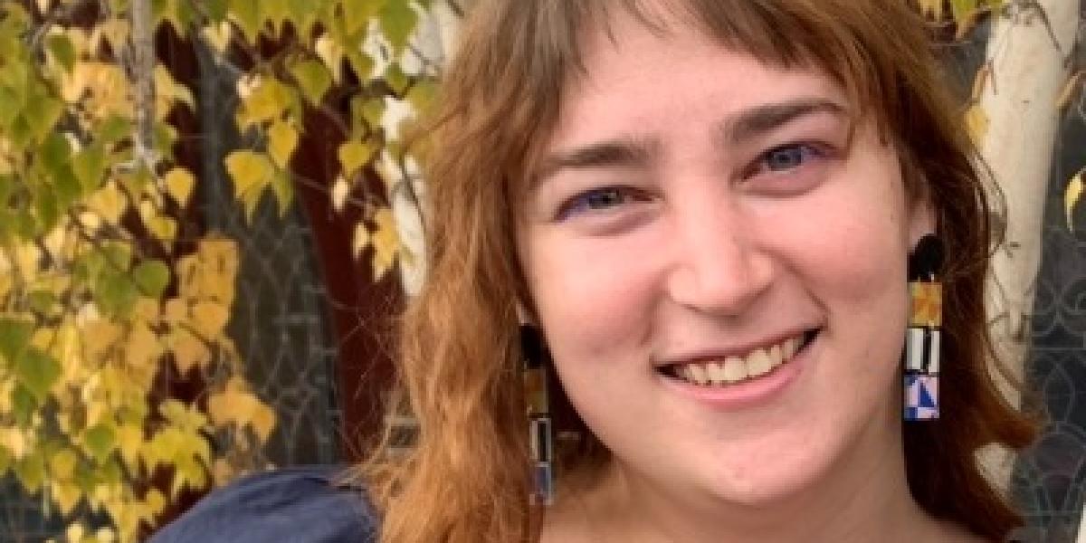 Emma Wilder in front of some aspen with yellow leaves.