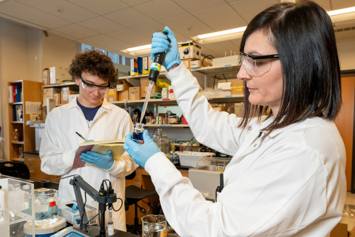 Man and woman in white lab coats conducting experiments in a lab.