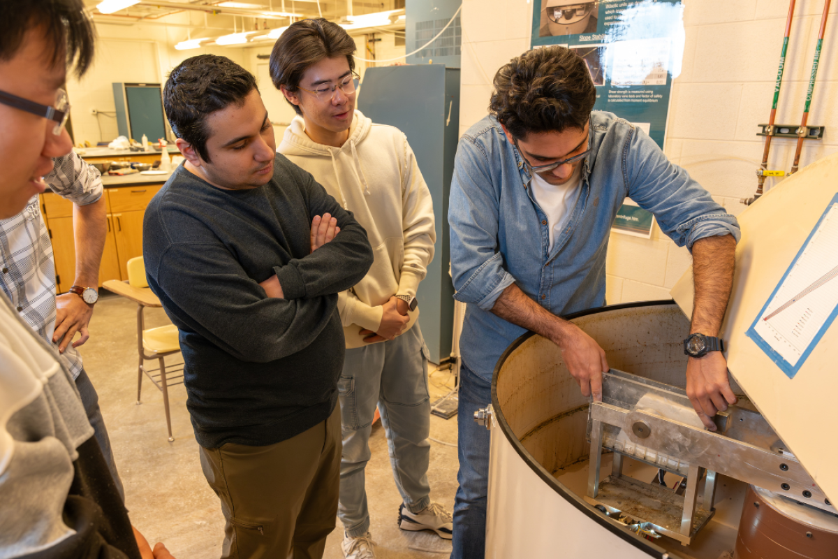 Four male graduate students working on equipment in a lab.
