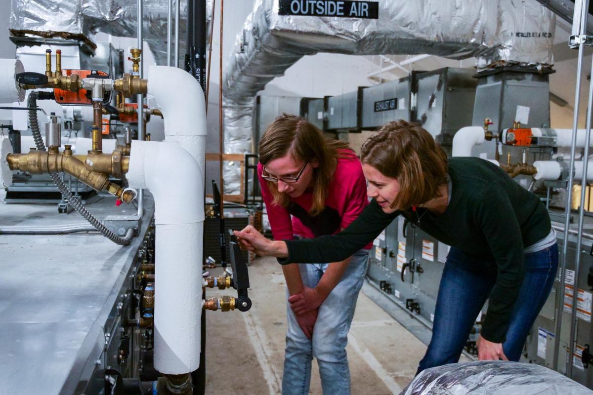 Two students checking the temperature and pressure settings for a rooftop HVAC unit in the Larson Laboratory.