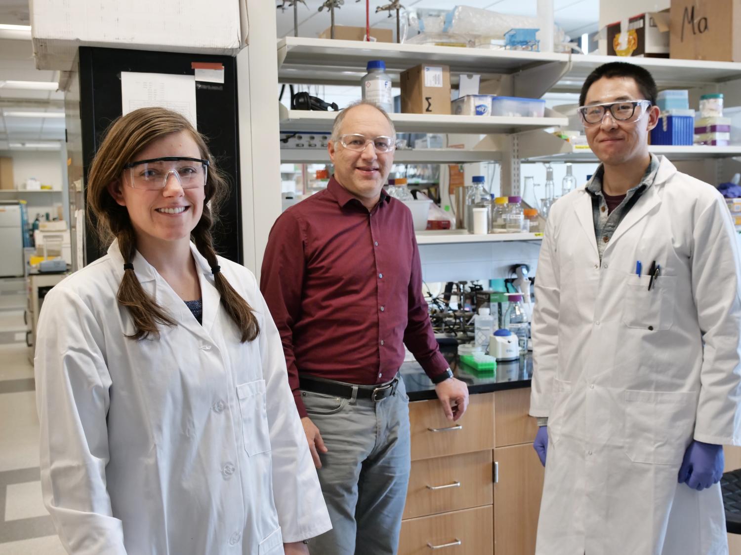 Karl Linden stands in his lab with two grad students.