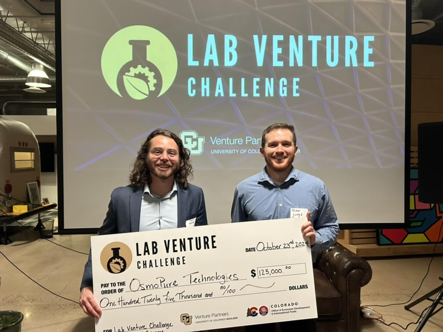 Tony. Straub and Kian Lopez hold a very large check in front of a screen that say "Lab Venture Challenge