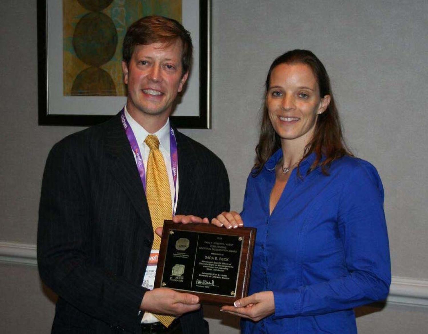 Sara Beck and an AEESP member hold the plaque Beck received to commemorate her dissertation award.