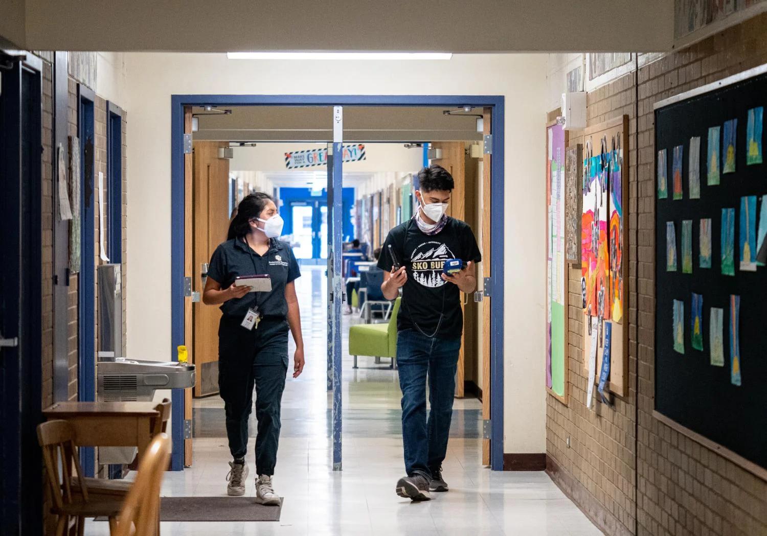 CU Boulder alumna Halle Sago, left, and undergraduate student Ricardo Reyes, right, visit High Peaks Elementary School in Boulder, Colorado, to monitor air quality.