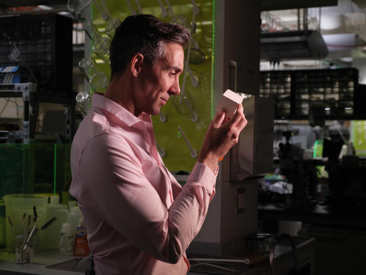 Wil Srubar looking at a block of his algae-derived concrete.