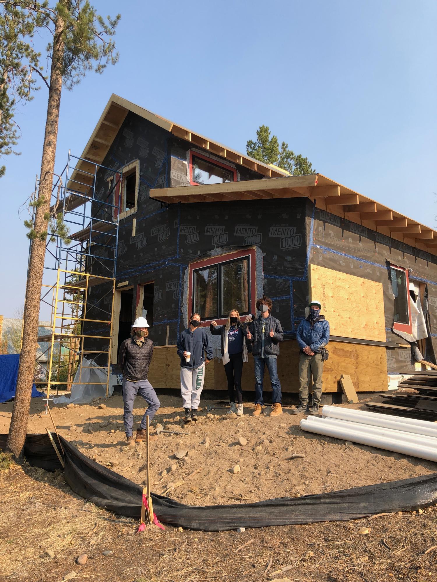 Students stand by a home they are building that was ultimately chosen from the design proposals.