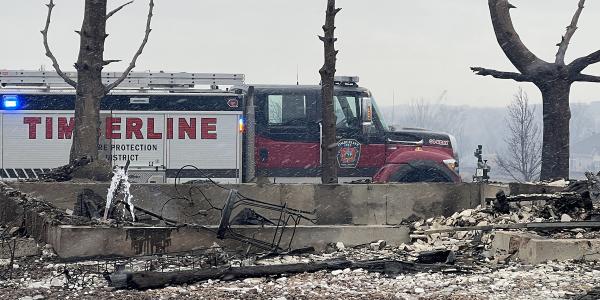 Water discharging from an open pipe into the foundation of a burned property.