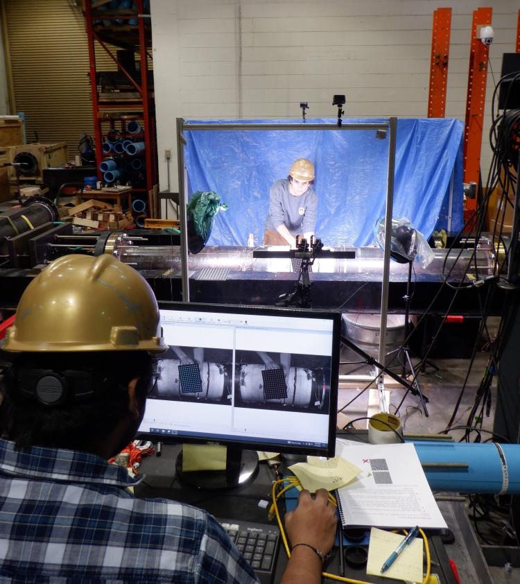 A researcher in a hard hat looks at a video screen