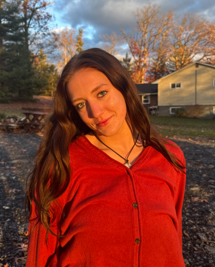 Angela Mink photographed during the "golden hour," with a house, trees and clouds in the background.