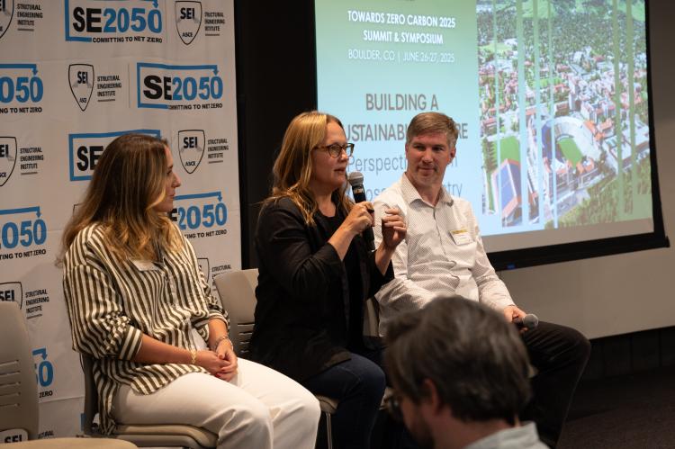 Amanda Kaminsky, holding a mic and in the middle of two other presenters, shares her perspective on what is motivating building owners to prioritize sustainability during the symposium. A slide advertising the symposium is in the background.