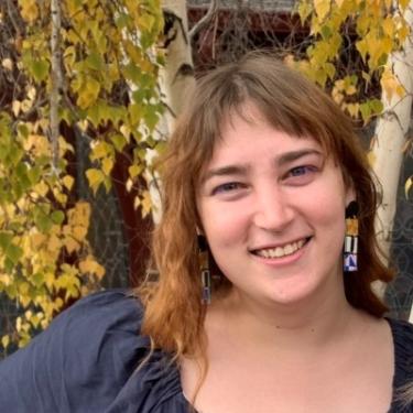 Emma Wilder in front of some aspen with yellow leaves.