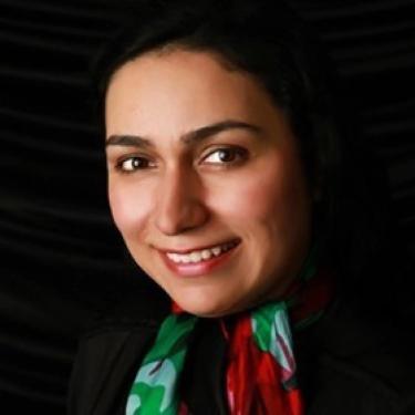Azadeh Bolhari wearing a colorful scarf. The background is dark.