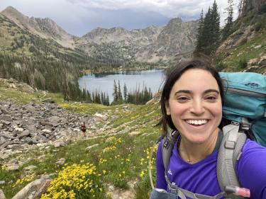 Meg Parker with a backpack on in front of an alpine lake.