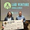 Tony. Straub and Kian Lopez hold a very large check in front of a screen that say "Lab Venture Challenge