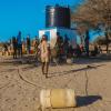 People lining up with plastic jugs to collect water.