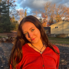 Angela Mink photographed during the "golden hour," with a house, trees and clouds in the background.