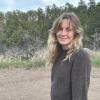 Macy Will standing in a sweater with some pine trees in the background.