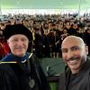 Karl Linden dressed in regalia and Marco Campos stand in front of the 2025 CEAE graduates.