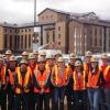 Group of people wearing construction vests and helmets.